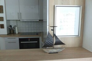 Eine Küche mit weißen Schränken, einem Geschirrspüler und einem kleinen Modell eines Segelboots auf der Arbeitsfläche.