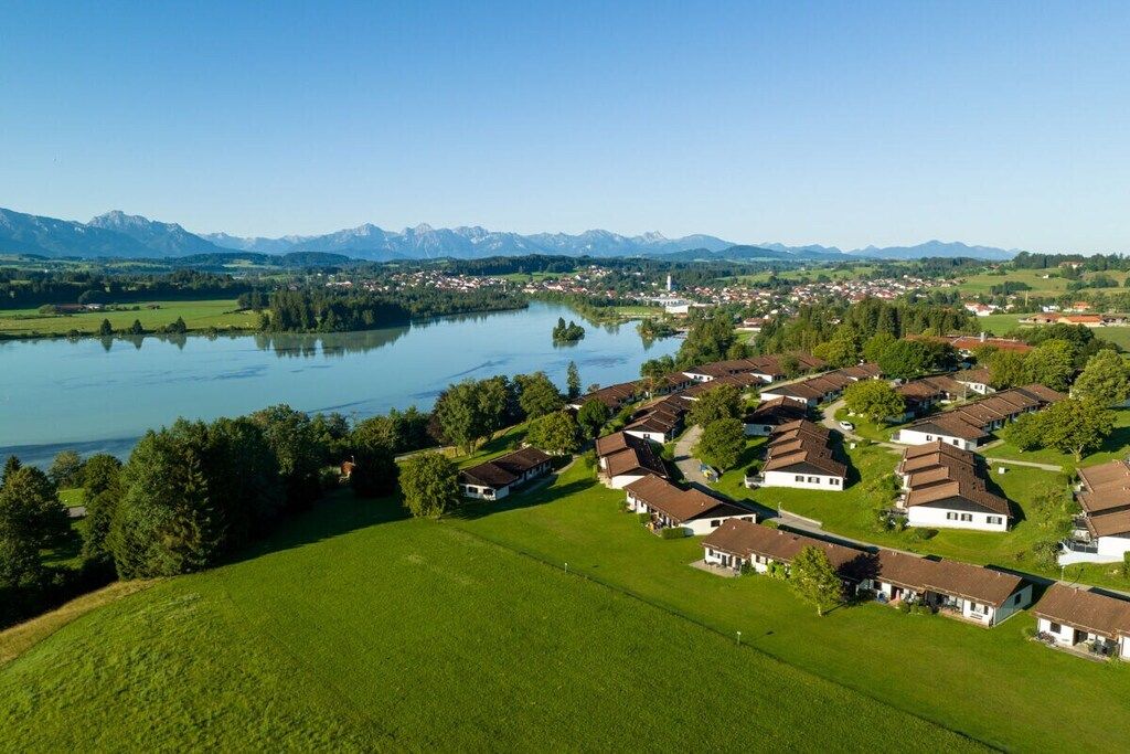 A residential area with houses and a lake, surrounded by mountains.