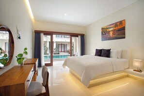 Una habitación de hotel moderna con una cama grande, un escritorio, una silla, una planta en maceta y vistas a una piscina y zona exterior.