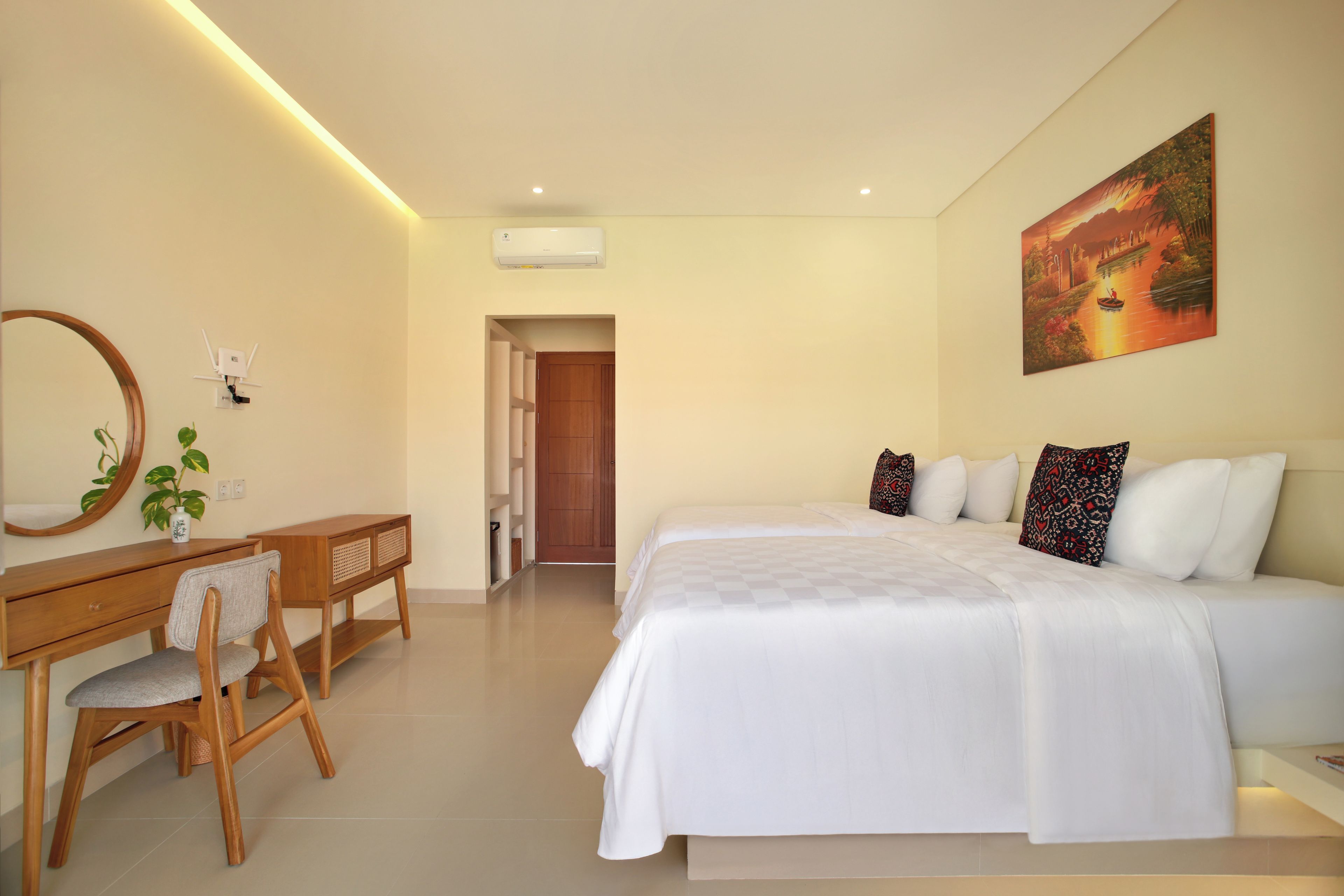 Quarto de hotel com cama, escrivaninha, cadeira, espelho e um quadro na parede.