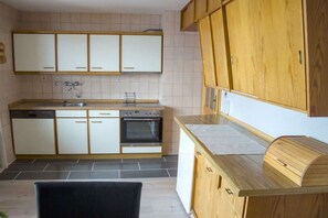 Eine Küche mit weißen Schränken, einem Geschirrspüler, einem Backofen und einer Holzarbeitsplatte.