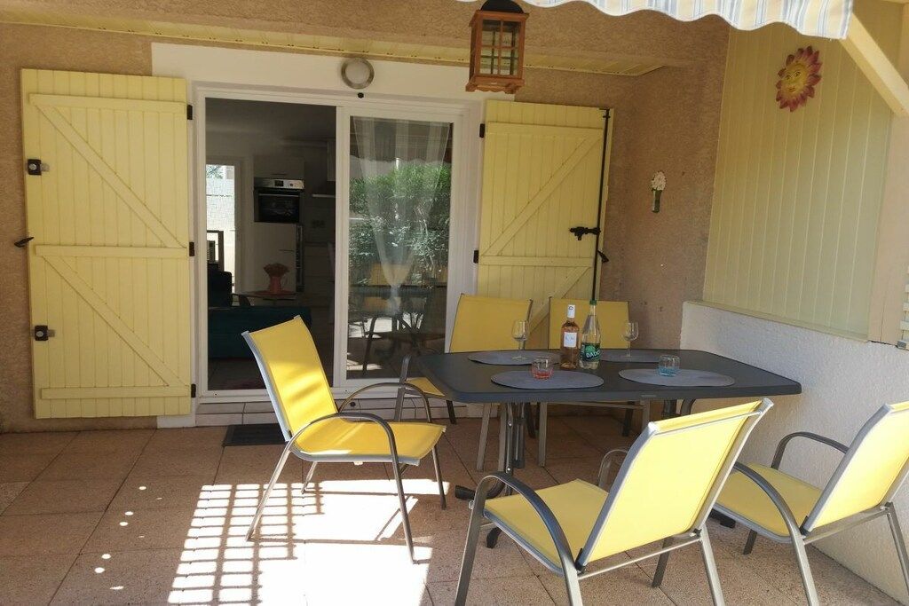 An outdoor patio with a table and chairs, a sliding glass door, and a lantern.