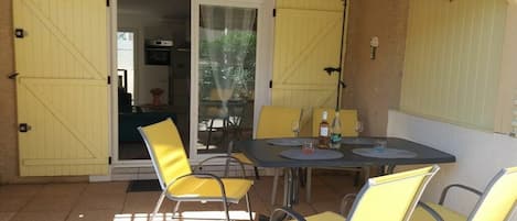 Un patio exterior con mesa y sillas, una puerta corrediza de vidrio y un farol.