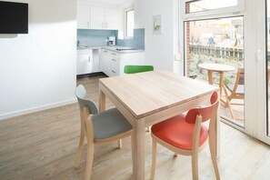 Eine moderne Küche mit weißen Schränken, einer blauen Spritzschutzwand und einem Essbereich mit Holztisch und -stühlen.