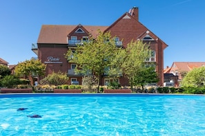 Ein großes Backsteingebäude mit einem Schwimmbad davor.