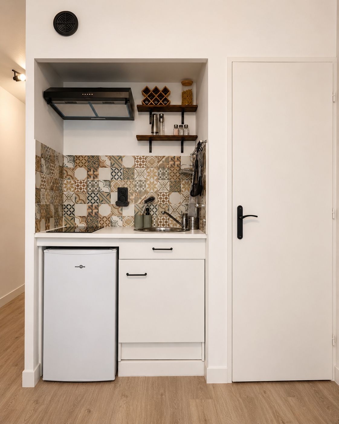 Une petite cuisine équipée comprenant un réfrigérateur intégré, un four à micro-ondes et une cuisinière.
