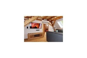 A loft-style living room with a television, wooden entertainment unit, and a sofa. - Holiday home Lotus Hof Stallegg (Löffingen)