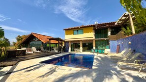 A pool area with lounge chairs, a covered seating area, and a building with a tiled exterior. - Country house in Itatiba, São Sebastião retreat (Itatiba)