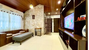 Una sala de estar con una pared de piedra, un sofá, una mesita y un televisor.