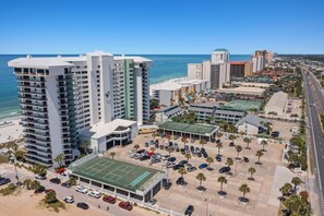 Ein Hochhaus-Hotel mit mehreren Etagen, einem Parkplatz und Blick auf den Strand.