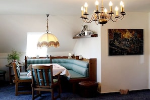 A dining area with a round table, chairs, a bench, a chandelier, and a painting on the wall. - Holiday apartment with 1 bedroom (Gschwend-Frickenhofen)