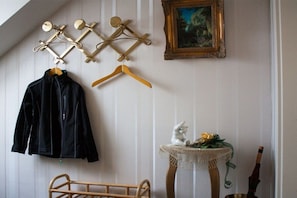 A room with a bed, a coat rack with a jacket, a small table with a decorative item, and a framed painting on the wall. - Holiday apartment with 1 bedroom (Gschwend-Frickenhofen)