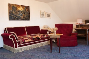 A room with a red sofa, a red armchair, a small table with a vase, and a painting on the wall. - Holiday apartment with 1 bedroom (Gschwend-Frickenhofen)