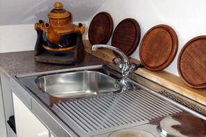 A kitchen with a stainless steel sink, wooden cutting board, and a wooden pot on the counter. - Holiday apartment with 1 bedroom (Gschwend-Frickenhofen)