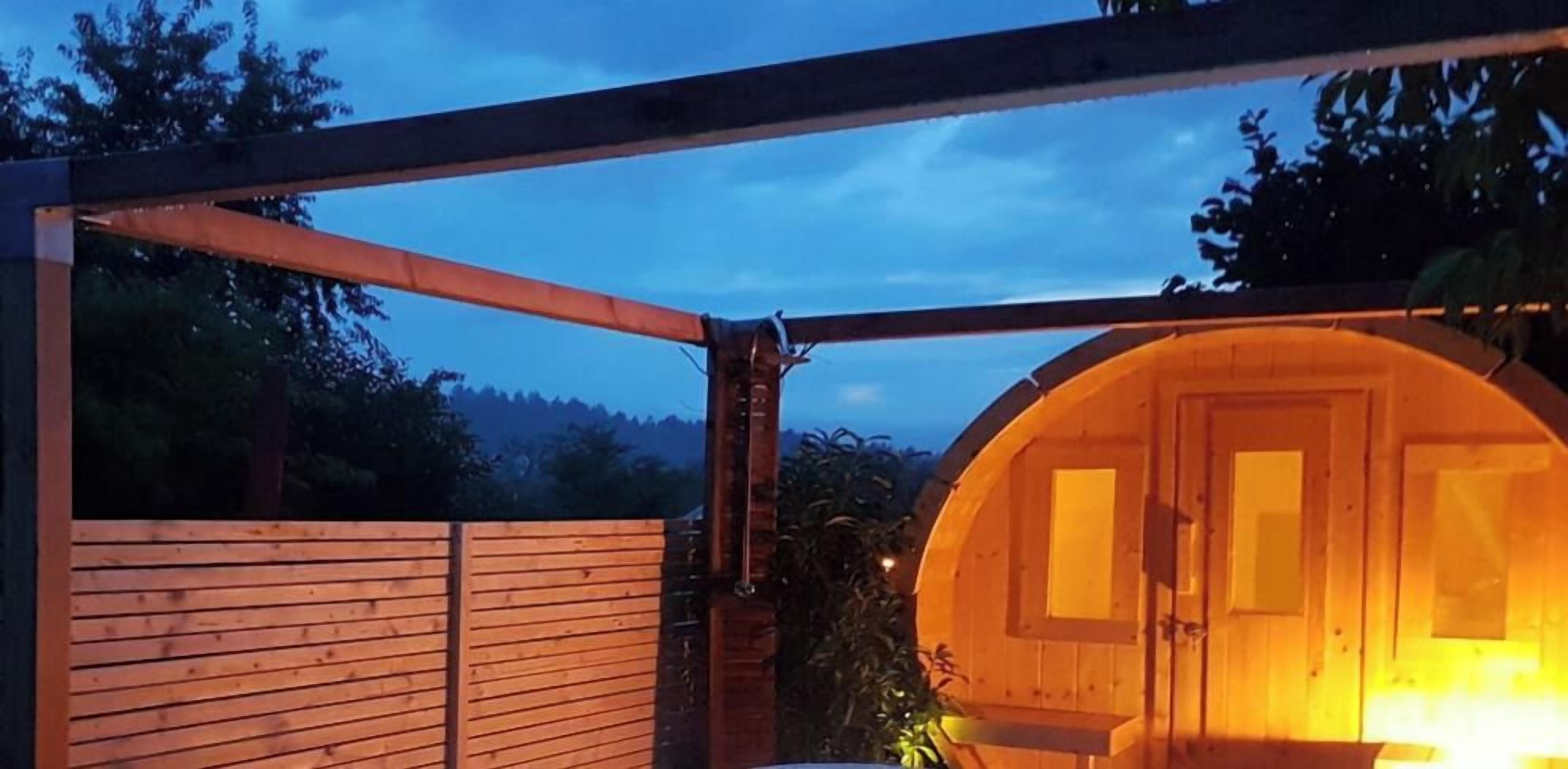 Une structure en bois dotée d’une porte circulaire et d’une clôture en bois.