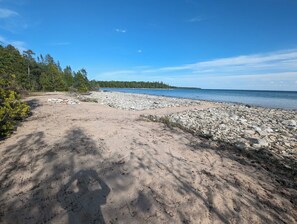 A natural beach with a rocky shoreline, trees, and a clear sky. - Soothing 3 Arce private campground on Lake Huron in lovely De Tour Village (De Tour Village)