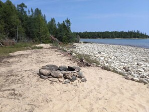 A rocky shoreline with a sandy area and a small pile of rocks. - Soothing 3 Arce private campground on Lake Huron in lovely De Tour Village (De Tour Village)