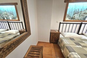 A bedroom with two beds, a wooden headboard, a small wooden nightstand, and a window with a view of trees. - Villa in Pitsidia with swimming pool (Pitsidia)