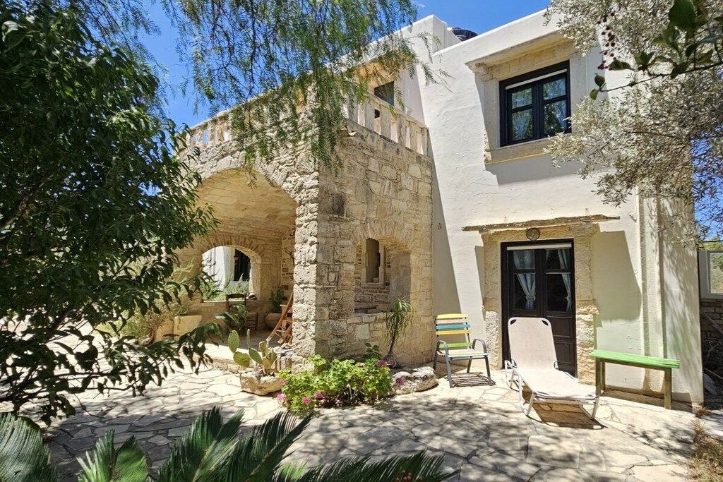 A stone building with a courtyard, a wooden bench, and a small table.