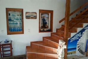 A staircase with terracotta tiles, wooden handrails, and a wall with framed artwork. - Villa in Pitsidia with swimming pool (Pitsidia)