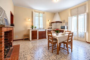 Une cuisine avec coin repas, comprenant une cheminée en briques, des plans de travail en granit et une table à manger pour quatre personnes.