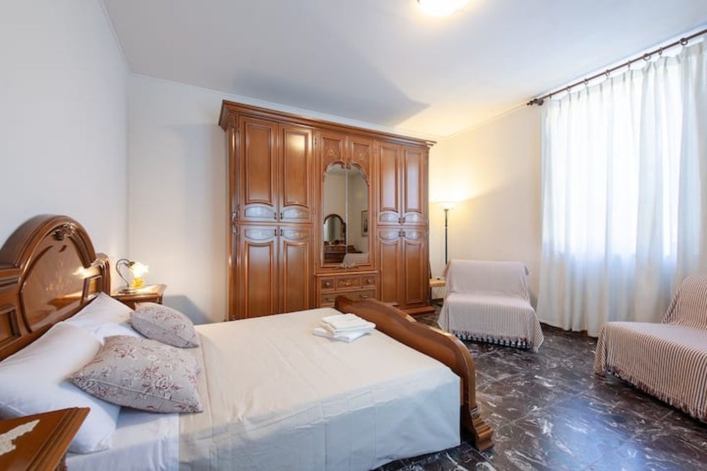 Ein Hotelzimmer mit Bett, Schrank, Stuhl und Nachttisch.