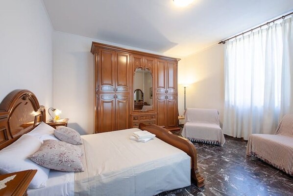 Une chambre d’hôtel avec un lit, une armoire, une chaise et une table de chevet.