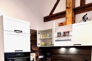 A kitchen with white cabinets, a built-in oven, and a wooden ceiling beam. - Holiday apartment with 1 bedroom (Landau in der Pfalz)