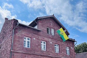 A red brick building with a flag, windows, and a clear sky. - Holiday apartment with 1 bedroom (Landau in der Pfalz)