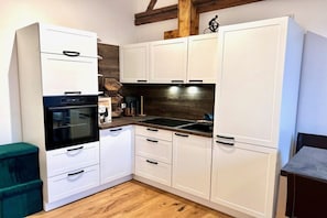 A compact kitchen with white cabinets, a built-in oven, and a dark backsplash. - Holiday apartment with 1 bedroom (Landau in der Pfalz)