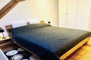 Een slaapkamer met een bed, nachtkastje, lamp en een garderobe.