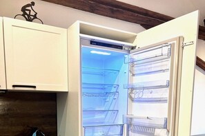 An open refrigerator with clear shelves and a handle on the door. - Holiday apartment with 1 bedroom (Landau in der Pfalz)