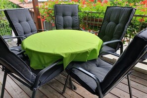 A round table with a green tablecloth surrounded by four black chairs on a wooden deck. - Holiday apartment with 4 bedrooms (Pegnitz)