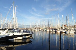 Ein Yachthafen mit mehreren angedockten Booten, ruhigem Wasser und blauem Himmel.