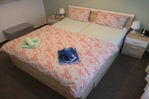 Une chambre d’hôtel avec un lit, une table de chevet, une commode et un petit banc.