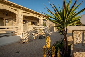A stone building with a covered walkway and a palm tree. - Villa in Kalamaki with swimming pool (Kalamaki)