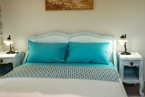 A bed with a patterned bedspread, two matching pillows, and two bedside lamps on white nightstands. - Villa in Kalamaki with swimming pool (Kalamaki)