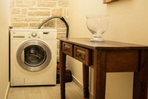 A compact laundry room with a washing machine, a wooden table, and a glass bowl. - Villa in Kalamaki with swimming pool (Kalamaki)
