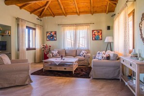 A living room with a wooden ceiling, a sofa set, a coffee table, and a lamp.