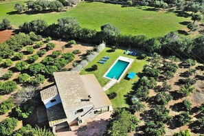 A house with a swimming pool, surrounded by a garden with trees and a lawn.