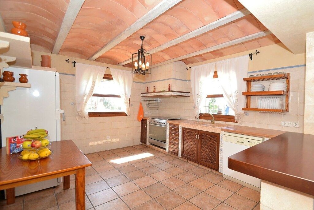A kitchen with a tiled floor, wooden cabinets, a refrigerator, an oven, and a sink.