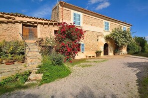 A stone building with a wooden door, a window with blue shutters, and a gravel driveway. - Finca in Llubi with swimming pool (Llubi)