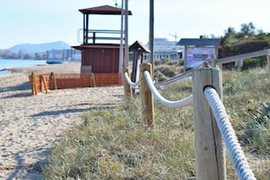 A beach with a lifeguard tower, wooden fence, and a wooden post with a rope. - Finca in Llubi with swimming pool (Llubi)
