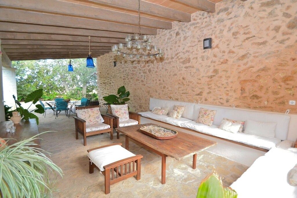 A stone-walled room with a wooden ceiling, a white sofa, and a wooden table.
