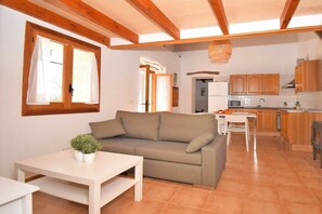 A cozy living room with a sofa and a table, a kitchen with wooden cabinets, and a dining area.