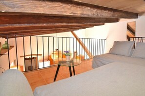 A bedroom with a sloped ceiling, a glass table with a plant, and a view of a staircase.
