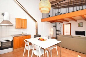 A modern kitchen with white cabinets, a stove, and a dining area with a table and chairs.