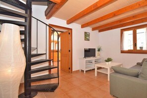 A living room with a spiral staircase, a television, a sofa, and a window.