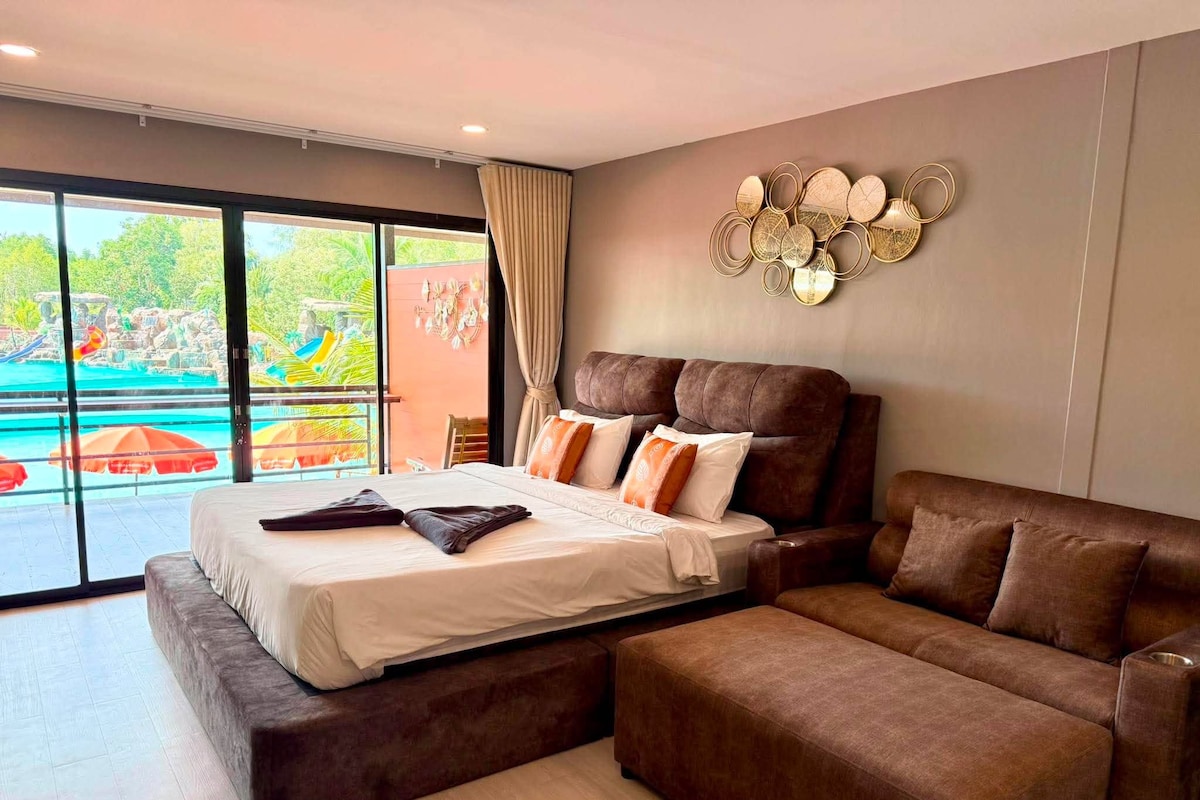 Quarto moderno com uma cama grande, um sofá e vista para a área da piscina externa.