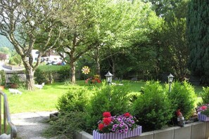 Ein Garten mit einem Weg, einem weißen Zaun und einem Haus im Hintergrund.